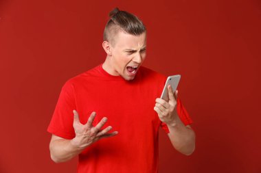 Renkli arka planda cep telefonu ile Kızgın genç adam