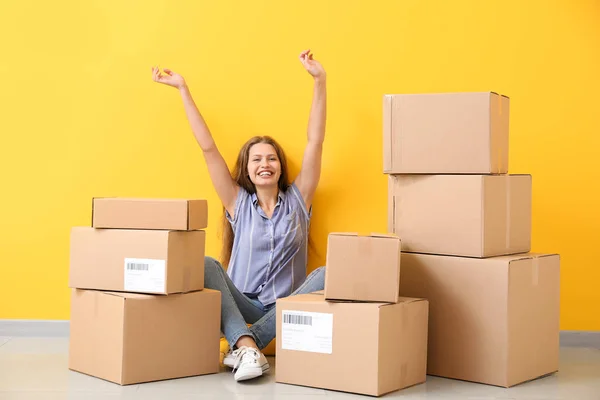 Young woman with many cardboard boxes near color wall — Stock Photo, Image