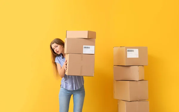 Mladá žena s lepenkovou krabicí na barevném pozadí — Stock fotografie