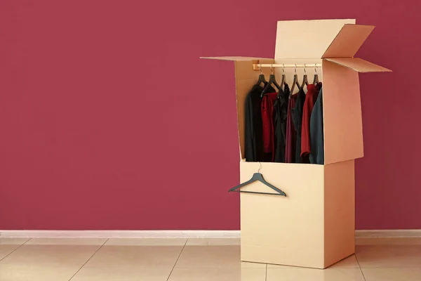 Wardrobe box with clothes near color wall