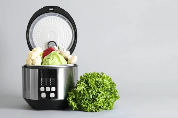 Modern multi cooker and vegetables on light background — Stock Photo, Image