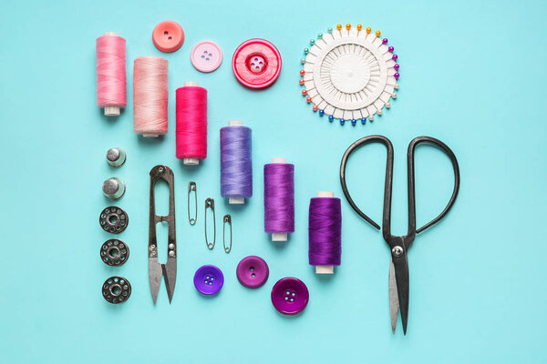 Sewing threads and accessories on color background