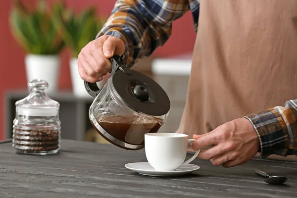Чоловік вливає каву в чашку вдома, крупним планом — стокове фото