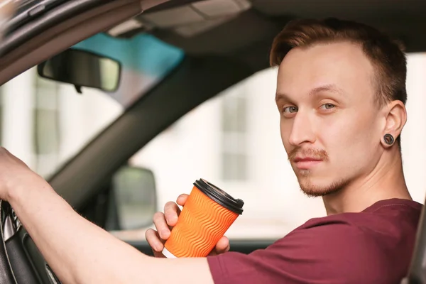 Handsome man drinking coffee in car