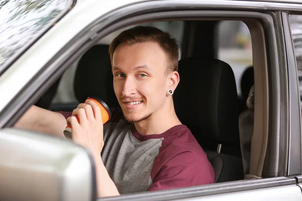 Handsome man drinking coffee in car