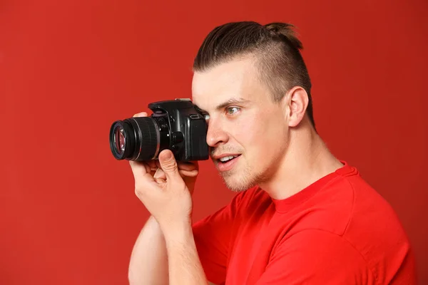 Knappe jonge man met fotocamera op kleur achtergrond — Stockfoto