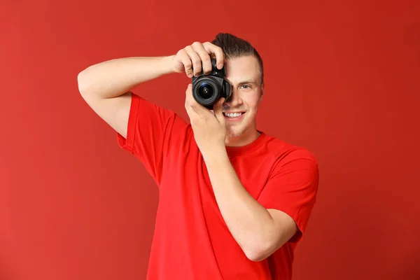 Knappe jonge man met fotocamera op kleur achtergrond — Stockfoto