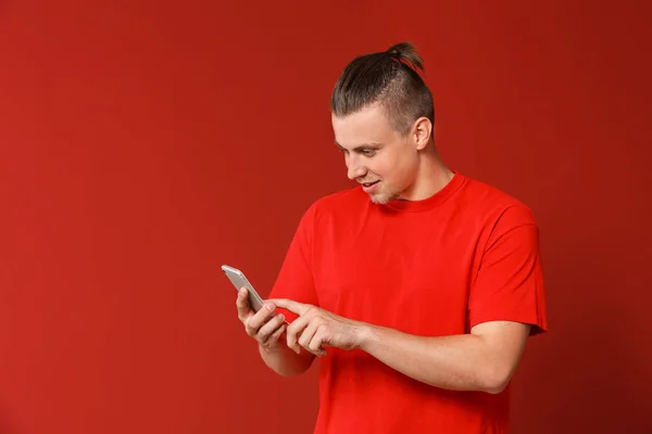 Jovem bonito com telefone celular no fundo de cor — Fotografia de Stock