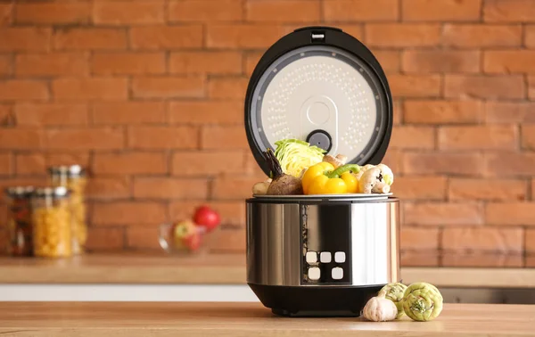 Modern multi cooker with vegetables on kitchen table — Stock Photo, Image