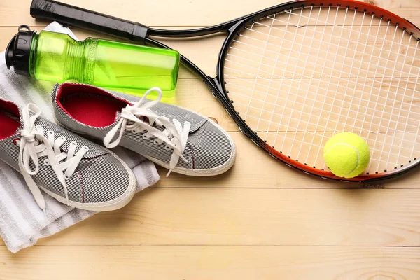 Тенісна ракетка, взуття, рушник, пляшка води і м'яч на дерев'яному фоні — стокове фото