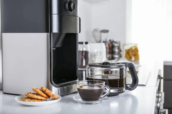 Modern coffee machine and hot beverage on kitchen table — Stock Photo, Image