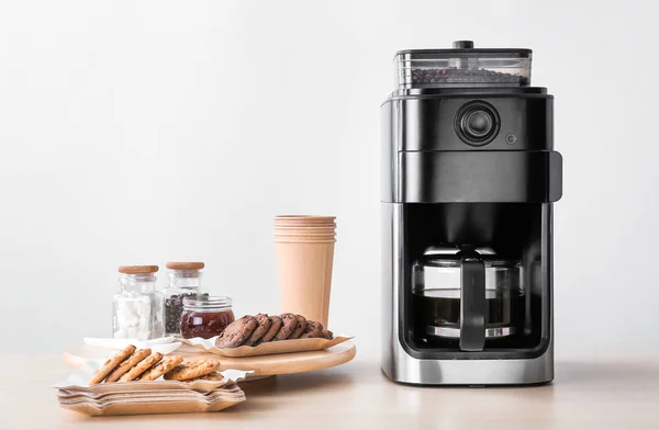Modern coffee machine and sweets on kitchen table — Stock Photo, Image
