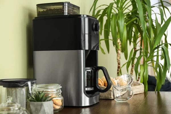 Modern coffee machine and sweets on kitchen table — Stock Photo, Image