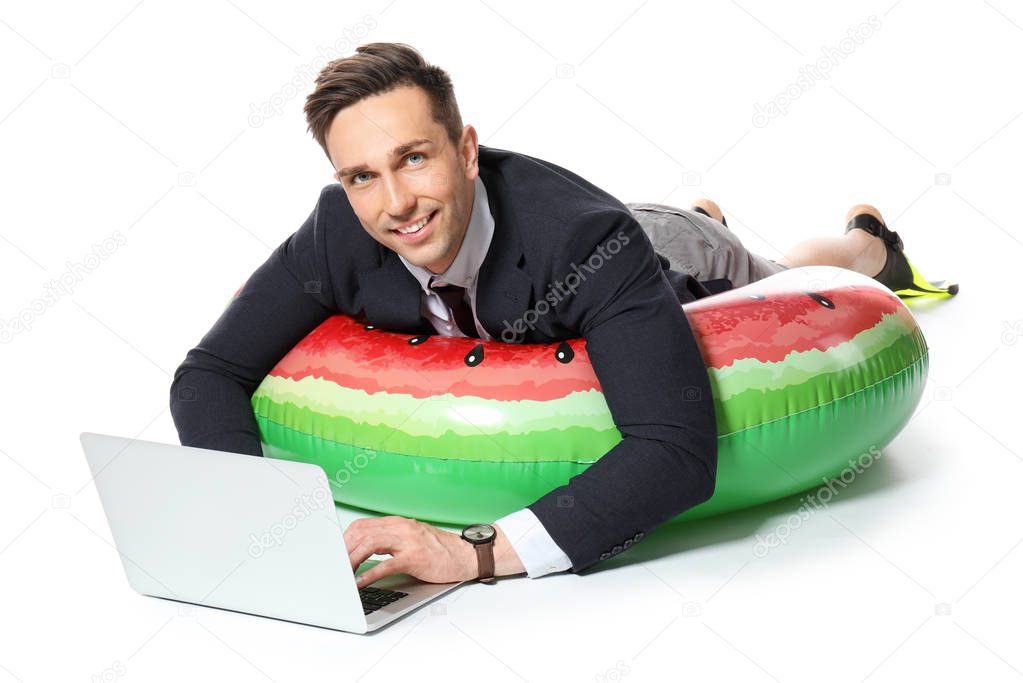 Handsome accountant with laptop and swimming ring dreaming about vacation on white background