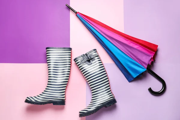 色の背景にスタイリッシュな傘とガンブーツ — ストック写真
