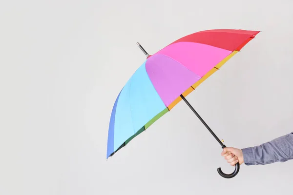 Female hand with stylish rainbow umbrella on light background — Stock Photo, Image