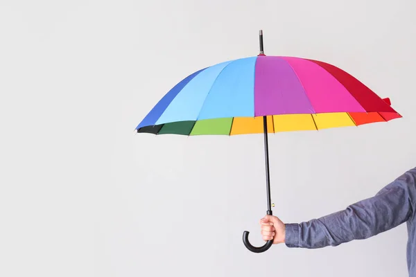 Female hand with stylish rainbow umbrella on light background — Stock Photo, Image