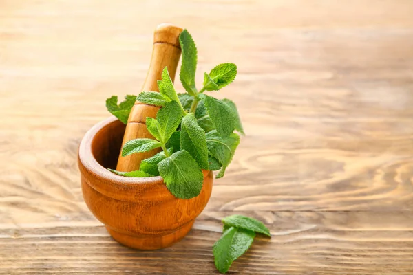 Argamassa com hortelã verde fresca e pilão sobre fundo de madeira — Fotografia de Stock