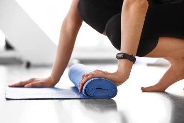 Genç kadın spor salonunda yoga minderi seriyor.