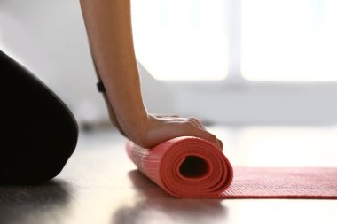 Genç kadın spor salonunda yoga minderi seriyor.