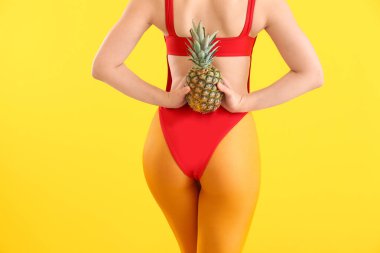 Yüzme takım elbiseli ve renkli arka planda ananas ile güzel genç kadın