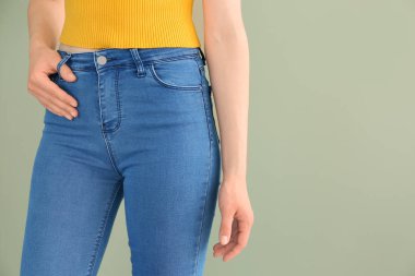 Renkli arka planda şık kot pantolon giyen genç kadın