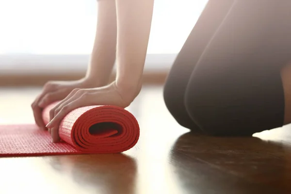 Mujer joven desplegando estera de yoga en el gimnasio — Foto de Stock