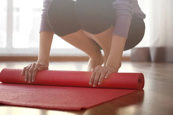Young woman rolling out yoga mat in gym