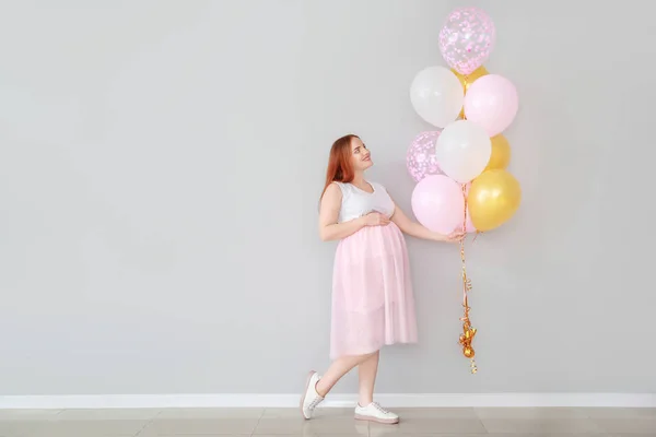 Schöne schwangere Frau mit Luftballons in der Nähe der Lichtwand — Stockfoto