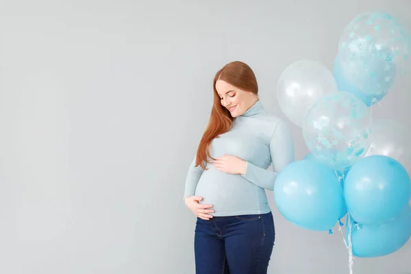 Piękna kobieta w ciąży z balonami na jasnym tle — Zdjęcie stockowe