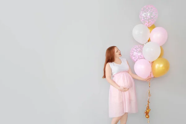 Beautiful pregnant woman with balloons on light background — Stock Photo, Image