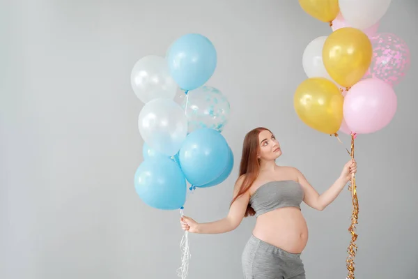 Piękna kobieta w ciąży z balonami na jasnym tle — Zdjęcie stockowe