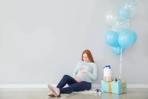 Красивая беременная женщина с ребенком душ подарки возле светлой стены — стоковое фото