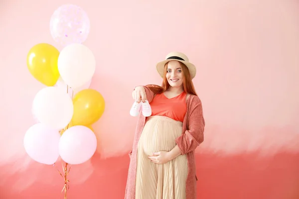 Vacker gravid kvinna med baby tossor och air ballonger på färgbakgrund — Stockfoto