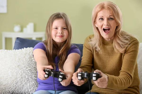 Mature woman and her cute granddaughter playing video game at home — Stock Photo, Image