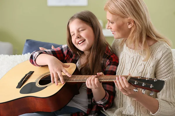 Little girl playing guitar for her grandmother at home