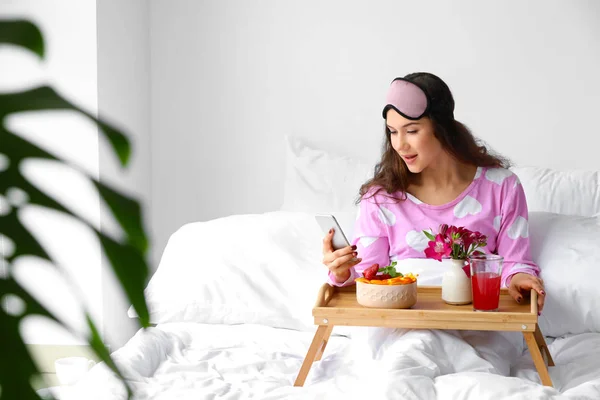 Krásná mladá žena s mobilním telefonem snímající v posteli — Stock fotografie