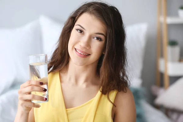 Beautiful young woman with glass of water at home — Stock Photo, Image