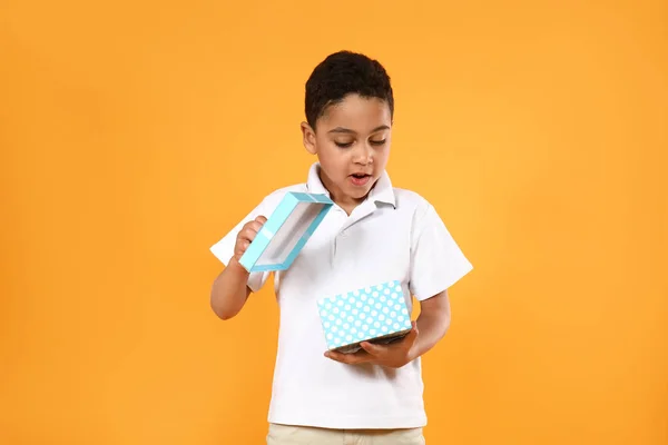 Ritratto di bambino carino con scatola regalo su sfondo a colori — Foto Stock