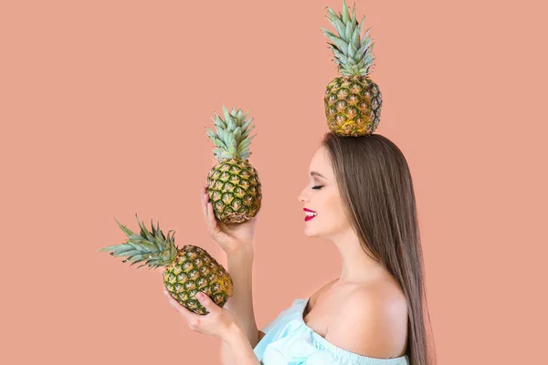 Beautiful young woman with pineapples on color background — Stock Photo, Image