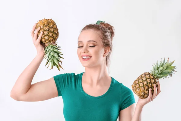Mooie jonge vrouw met ananassen op witte achtergrond — Stockfoto