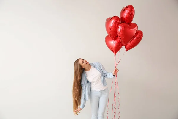 Mulher bonita com balões de ar em forma de coração no fundo claro — Fotografia de Stock