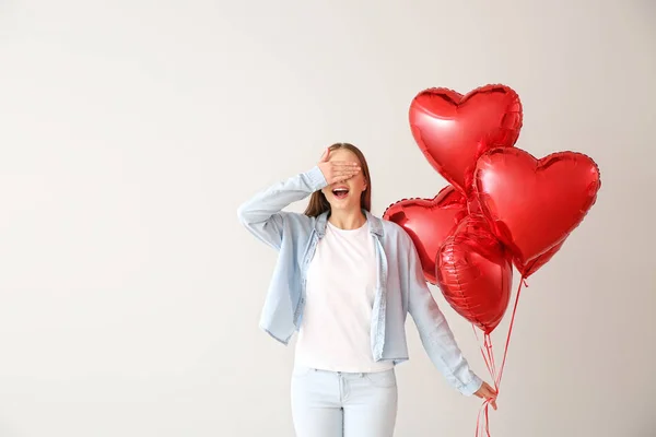 Bella giovane donna con palloncini d'aria a forma di cuore su sfondo chiaro — Foto Stock