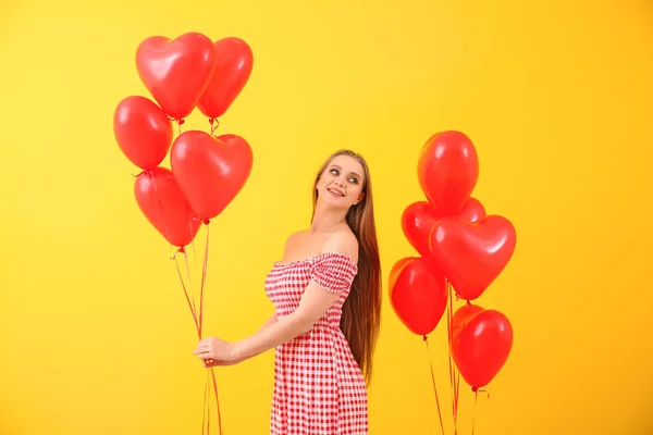 Hermosa mujer joven con globos de aire en forma de corazón en el fondo de color —  Fotos de Stock