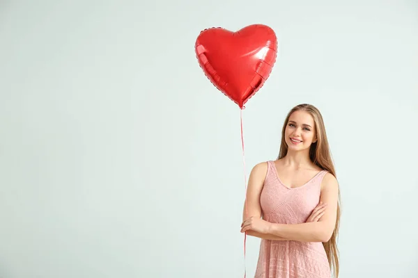 Mulher bonita com balão de ar em forma de coração no fundo claro — Fotografia de Stock