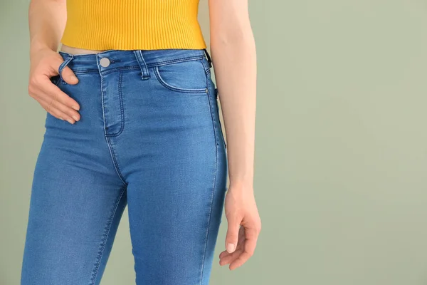 Jovem mulher vestindo calças jeans elegantes no fundo de cor — Fotografia de Stock