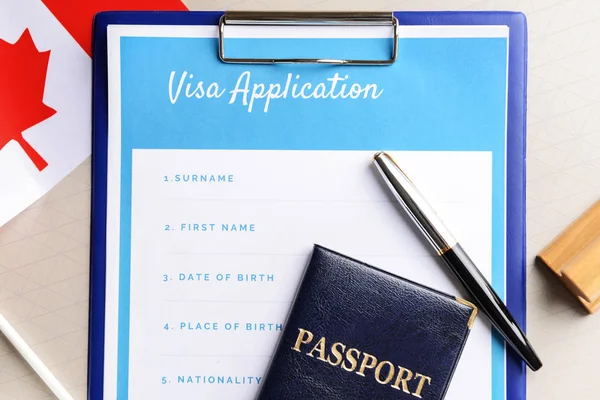 Visa application form, passport and Canadian flag on table. Concept of immigration