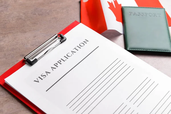 Visa application form, passport and Canadian flag on table, closeup. Concept of immigration