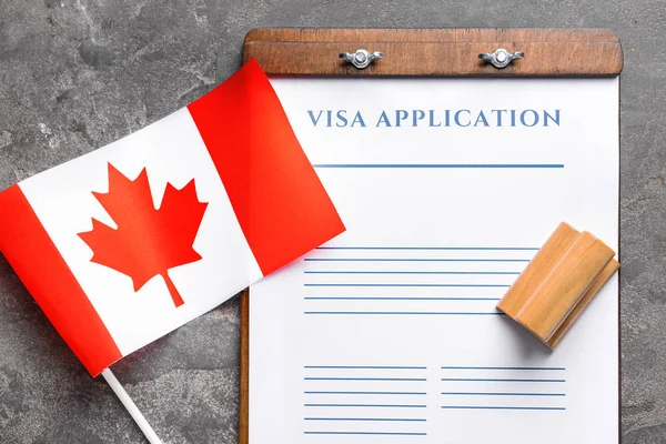 签证申请表、印章和加拿大国旗在桌子上。移民概念 — 图库照片