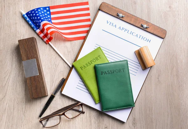 Visa application form, passports, stamp and USA flag on table. Concept of immigration